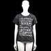 T-shirt - Black & Gray - Size M - Black and gray short-sleeve top with a round neck and straight hem. Features a floral-style overlay effect and white text graphic on the front, with rolled plain cuffs.