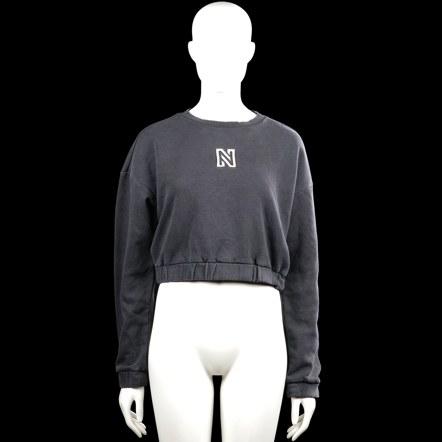 Nikkie - Sweatshirt - Charcoal - Size 32 - Charcoal solid sweatshirt with a round neck and long sleeves. Features a small chest logo and an elastic hem with plain cuffs.