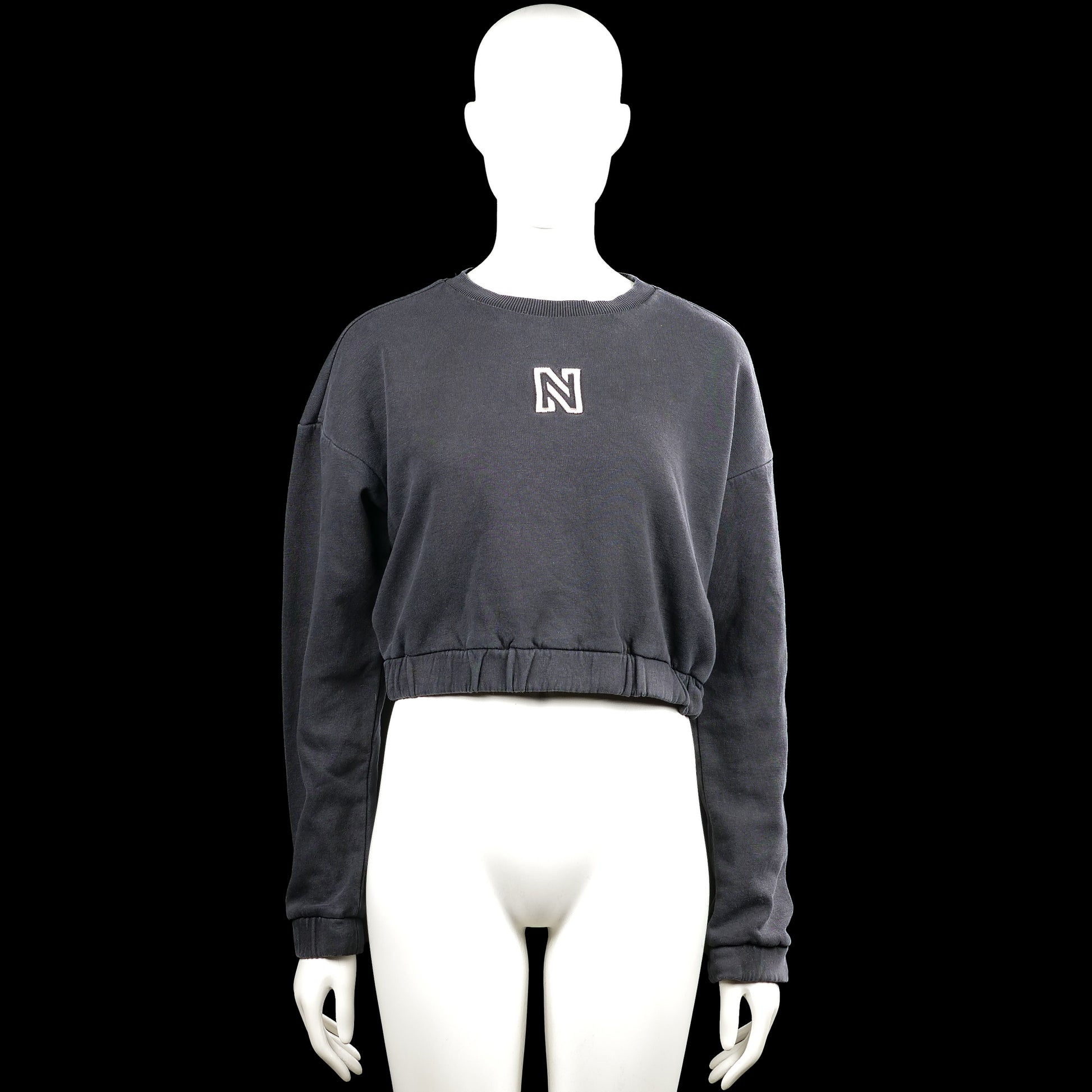 Nikkie - Sweatshirt - Charcoal - Size 32 - Charcoal solid sweatshirt with a round neck and long sleeves. Features a small chest logo and an elastic hem with plain cuffs.