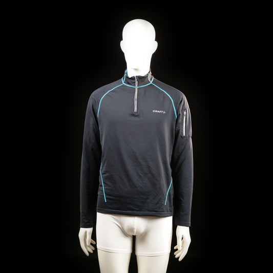 Craft - Sports top - Black & Light Blue - Size M - Long-sleeve sports top with a half-zip front, light blue contrast stitching, and a zip pocket on the upper left sleeve. High collar and fitted silhouette.