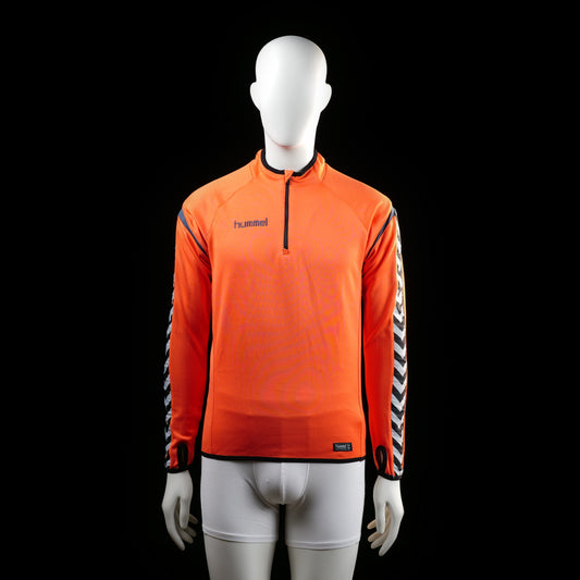 Hummel - Sports top - Orange & Black - Size 176 - Long-sleeve active top with a half-zip front and black trim at the hem and cuffs. Sleeves feature a bold black and white chevron pattern along the outer arm.