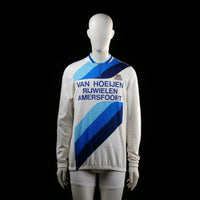 Ultima - Sports top - White & Light Blue - Size M - Long-sleeve zip-neck cycling jersey with diagonal blue-tone stripes and large printed text on the front and back. Features an elastic hem and rear pockets.