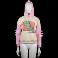 Hoodie - Ivory & Pink - Size S - Two-tone hoodie with ivory body and pink sleeves, featuring a green cartoon dinosaur print on the front and Japanese text. Hood has pink spikes on top and sleeves have matching 3D spike detailing.
