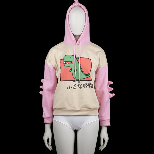 Hoodie - Ivory & Pink - Size S - Two-tone hoodie with ivory body and pink sleeves, featuring a green cartoon dinosaur print on the front and Japanese text. Hood has pink spikes on top and sleeves have matching 3D spike detailing.
